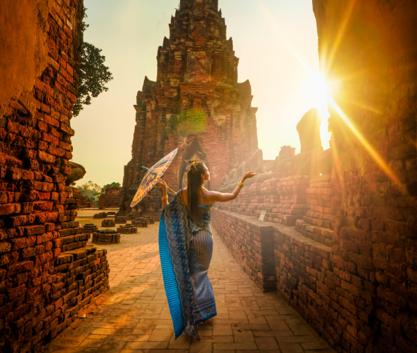 Image of lady with an umbrella walking between stone walls at sunset