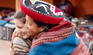 Royal Adventures staff embracing an Andean woman in Cusco